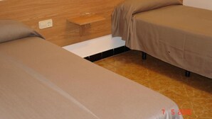 Ein Doppelzimmer mit zwei Betten, einem Nachttisch und einer Steckdose an der Wand.