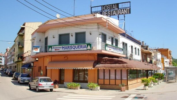 Ein Gebäude mit einem Schild für das Restaurant 'Marisqueria' und das Hotel-Restaurant.