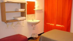 Ein Hotelzimmer mit zwei Betten, einem Waschbecken und einem Spiegel.