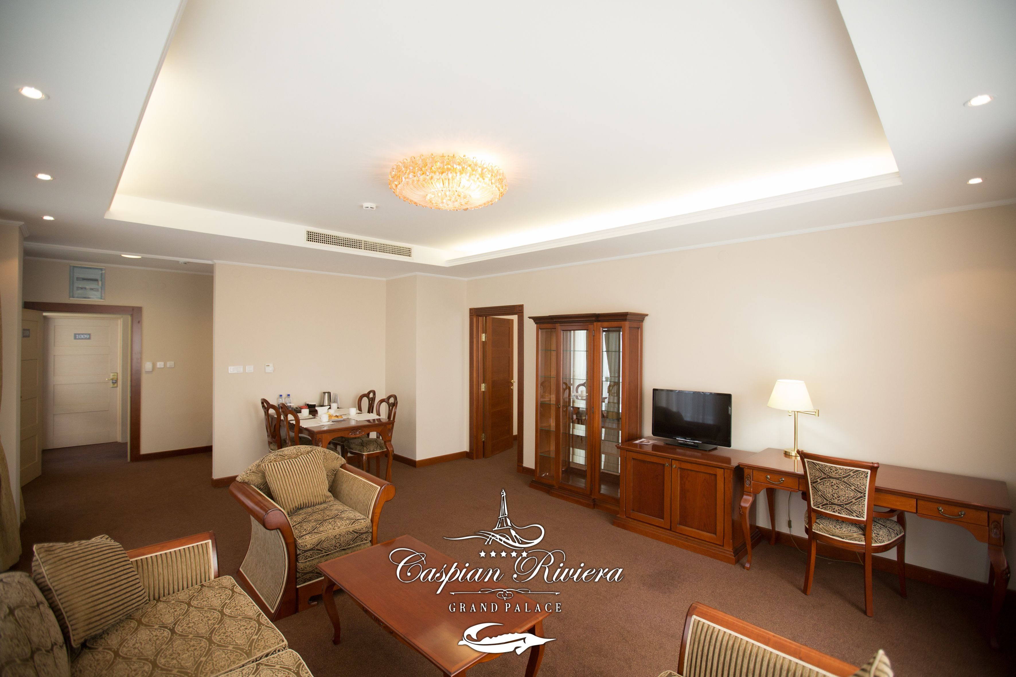 A spacious living room with a dining area, a television, and a desk.