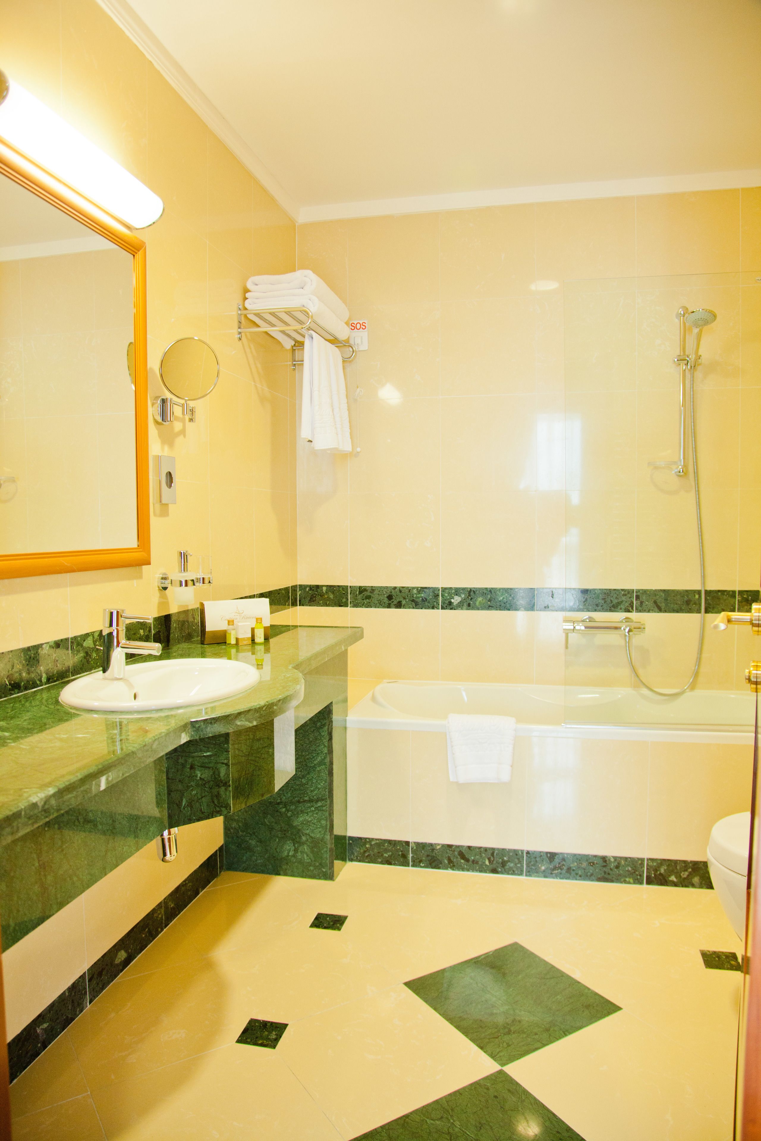 A bathroom with a sink, mirror, towel rack, and bathtub.