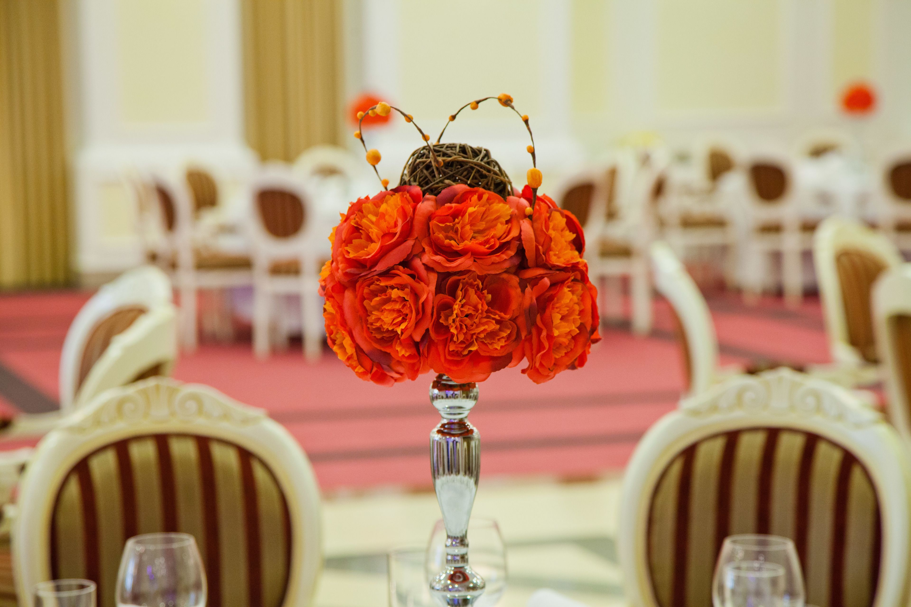 A table with a vase of red flowers and a decorative item resembling a bird.