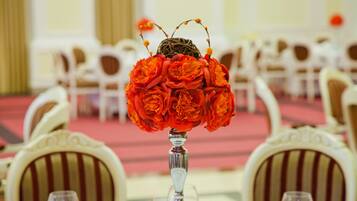 A table with a vase of red flowers and a decorative item resembling a bird.