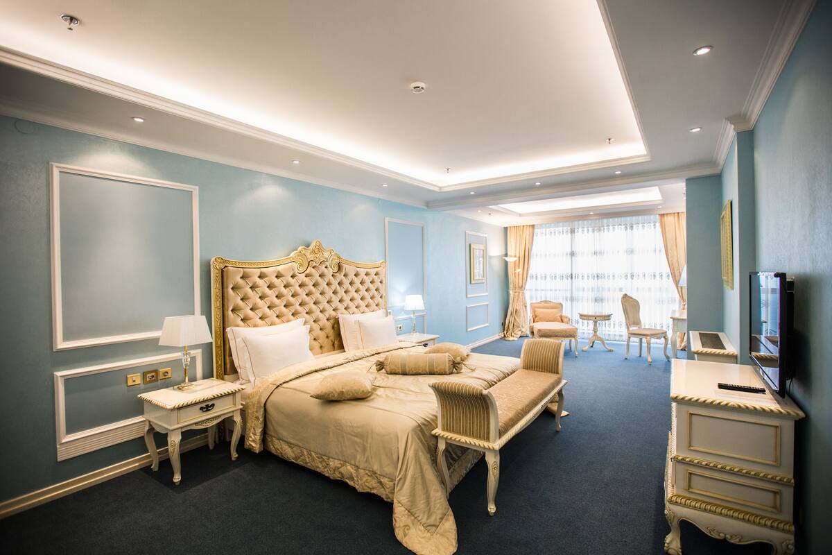 A spacious bedroom with a large bed, a television, and a seating area with a chair and table.