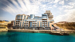 Een modern hotel met meerdere verdiepingen, een ligging aan het water en een opvallende glazen gevel.