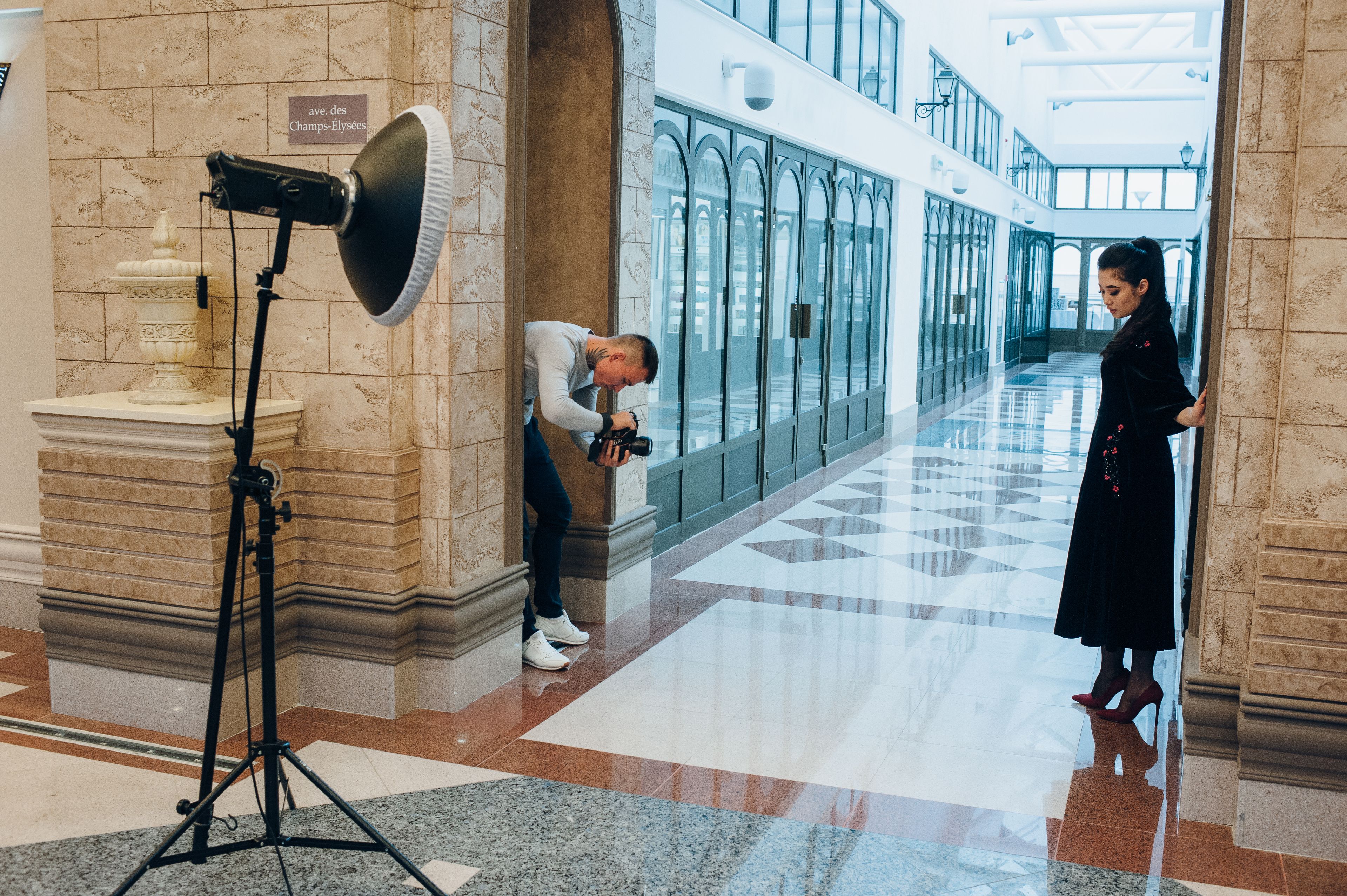 Un pasillo con suelo de mármol, un equipo de cámara y una persona tomando una fotografía.