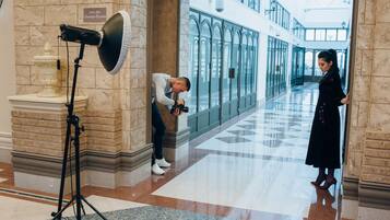 Un pasillo con suelo de mármol, un equipo de cámara y una persona tomando una fotografía.