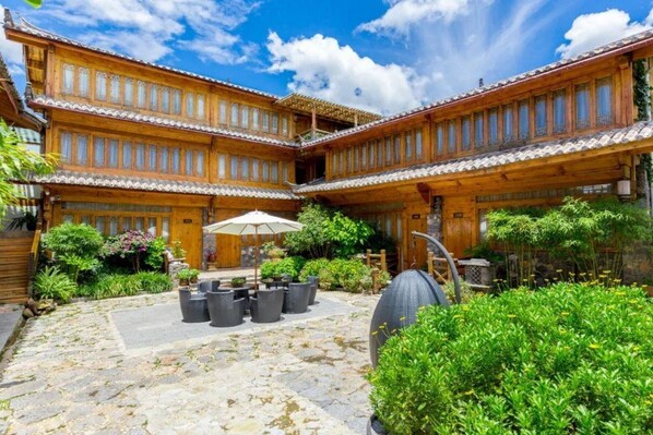 A traditional wooden building with a courtyard, stone pathway, and potted plants. - Lijiang E Outfitting Boutique Hotel (Lijiang)