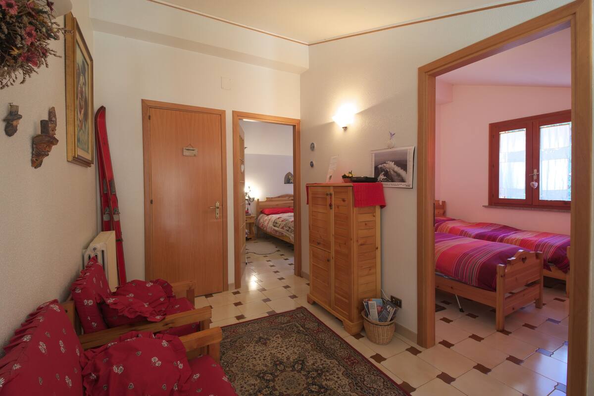 Un dormitorio con dos camas, un armario de madera, un radiador y una ventana pequeña.