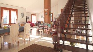 A spacious living area with a dining table, chairs, a sofa, and a staircase. - Magma Guest House (Ragalna)