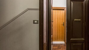 Un pasillo con una puerta de madera, un interruptor de luz y piso de madera.