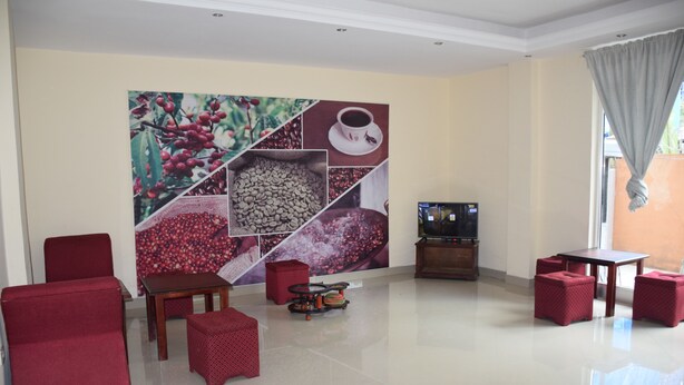 Un vaste salon agrémenté d’une grande fresque représentant des grains de café, de meubles rouges, d’un téléviseur à écran plat et d’un coin repas.