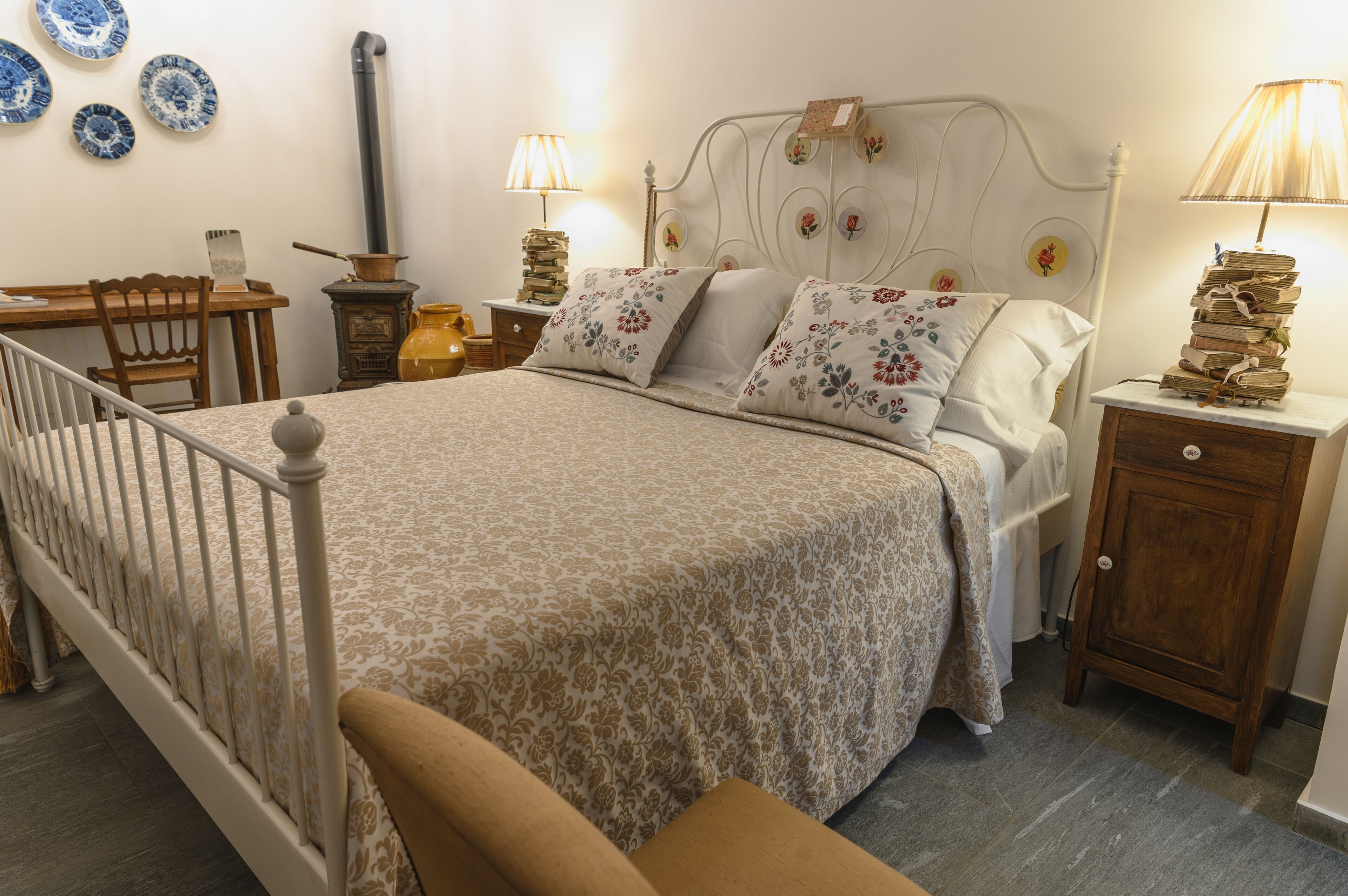 Une chambre à coucher avec un lit, une table de chevet, une chaise en bois, un bureau et une lampe.