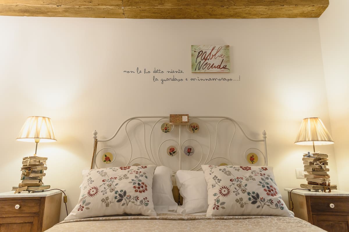 Un dormitorio con una cama, dos mesitas de noche y una pared decorada con una cita y un cuadro enmarcado.