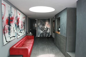 En modern entréhall med en röd bänk, en stor abstrakt målning och en väggmålning med motorcykelmotiv.