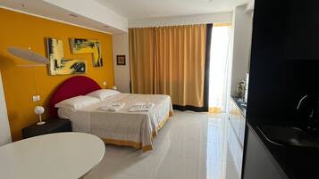 Una habitación de hotel moderna con cama, mesa de comedor y zona de cocina.