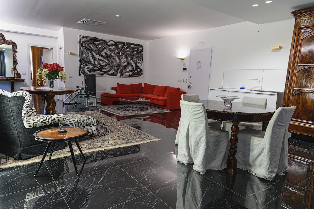 Una sala moderna con un sofá rojo, un sillón estampado y una mesa de centro redonda.