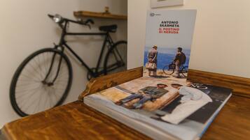 A book titled "Antonio Skårmåta Il destino di Neruda" on a wooden table with a bicycle in the background.