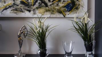 Tres plantas en macetas sobre una mesa, con un cuadro abstracto grande al fondo.