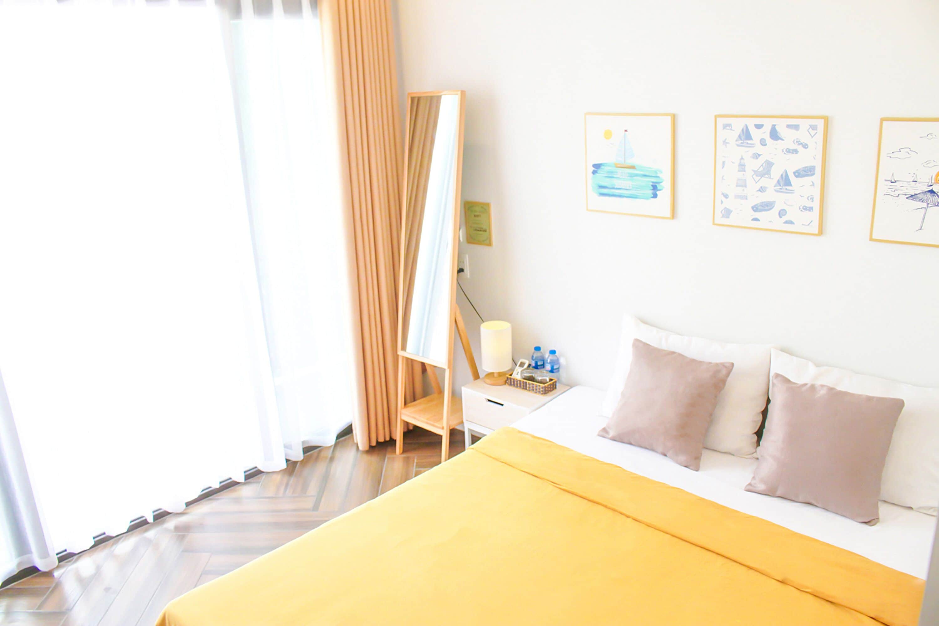 A hotel room with a bed, a bedside table with a lamp, and three framed pictures on the wall.