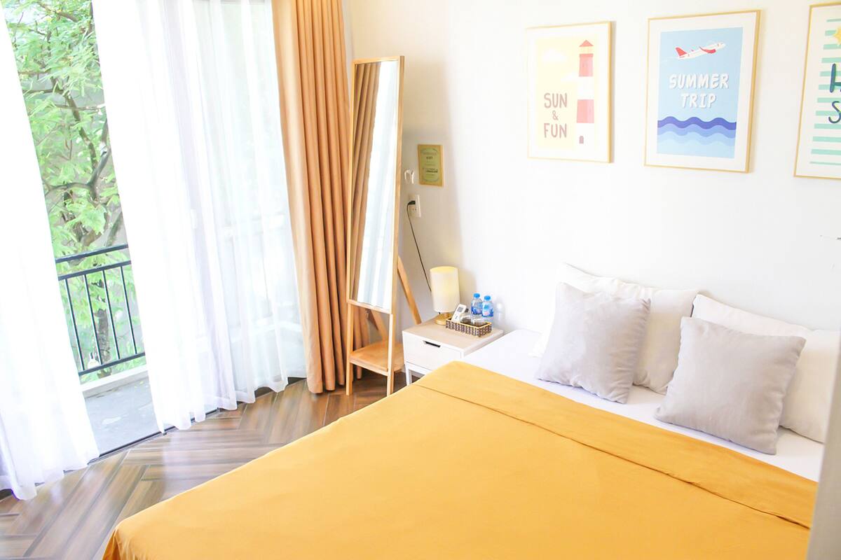 A hotel room with a bed, a desk, a chair, and a window with curtains.