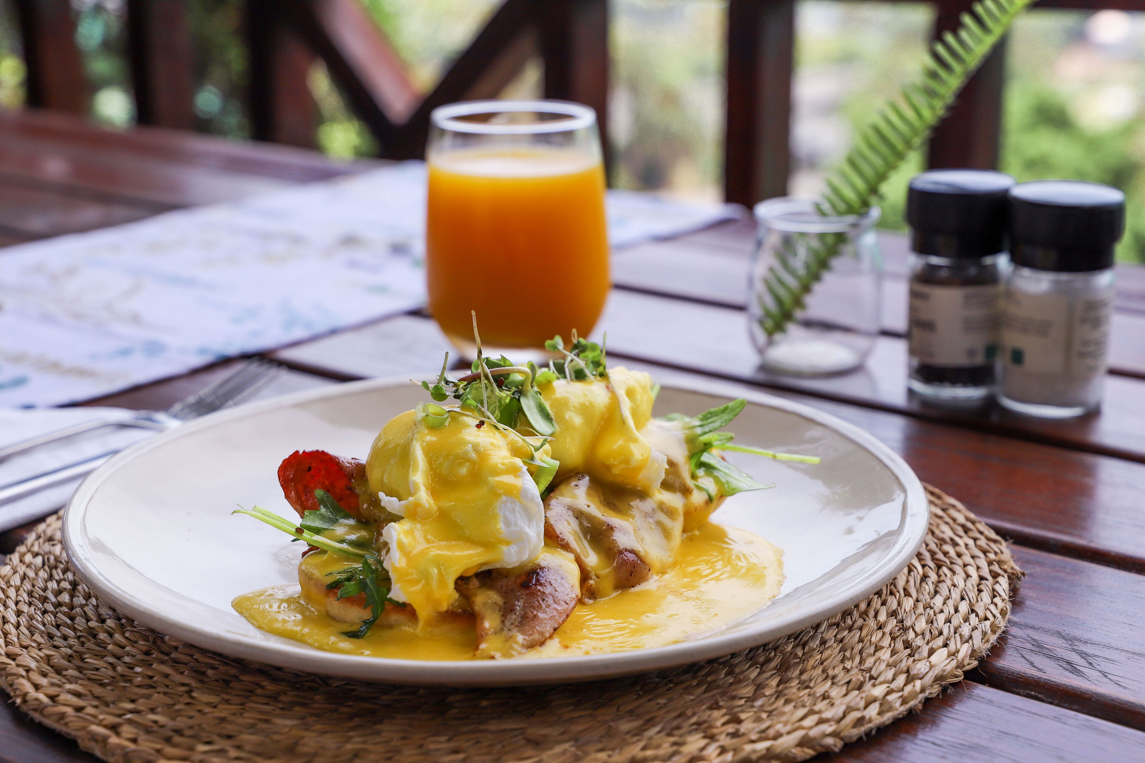 A plate of food with a glass of orange juice on a wooden table.