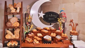 A bakery display with various baked goods, a crescent moon decoration, and a chalkboard sign. - Avari Xpress Multan (Multan)
