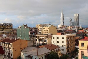 A cityscape with a mix of modern and older buildings, including a prominent skyscraper and a unique tower. - Dolphin hotel (Batumi)