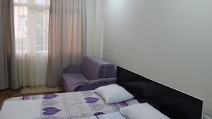 Um quarto com uma cama, uma cadeira e uma janela com cortinas.