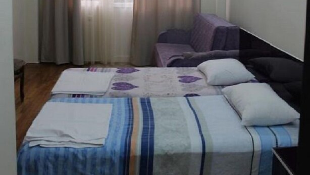 Quarto com cama, cadeira e janela com cortinas.