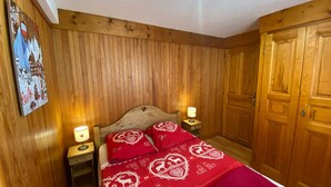 A wooden-paneled room with a bed, two bedside tables, and a ceiling fan. - Charming 2-room apartment, 4 pers, sunny view in Les Saisies (Les Saisies)