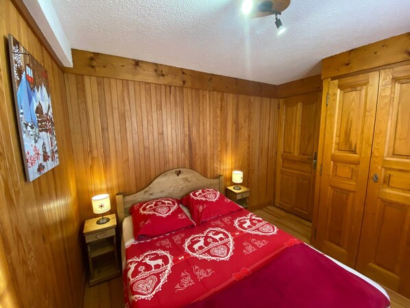 A wooden-paneled room with a bed, two bedside tables, and a ceiling fan. - Charming 2-room apartment, 4 pers, sunny view in Les Saisies (Les Saisies)