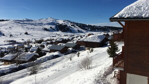 A snow-covered mountain village with wooden buildings and a ski slope. - Charming 2-room apartment, 4 pers, sunny view in Les Saisies (Les Saisies)