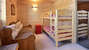 A wooden cabin room with bunk beds, a bench, and a small red cabinet. - Family apartment near slopes (La Plagne)