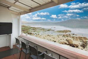 A balcony with a view of a beach, chairs, and a whiteboard. - Sea Cottage, Langebaan 4-Sleeper (Langebaan)