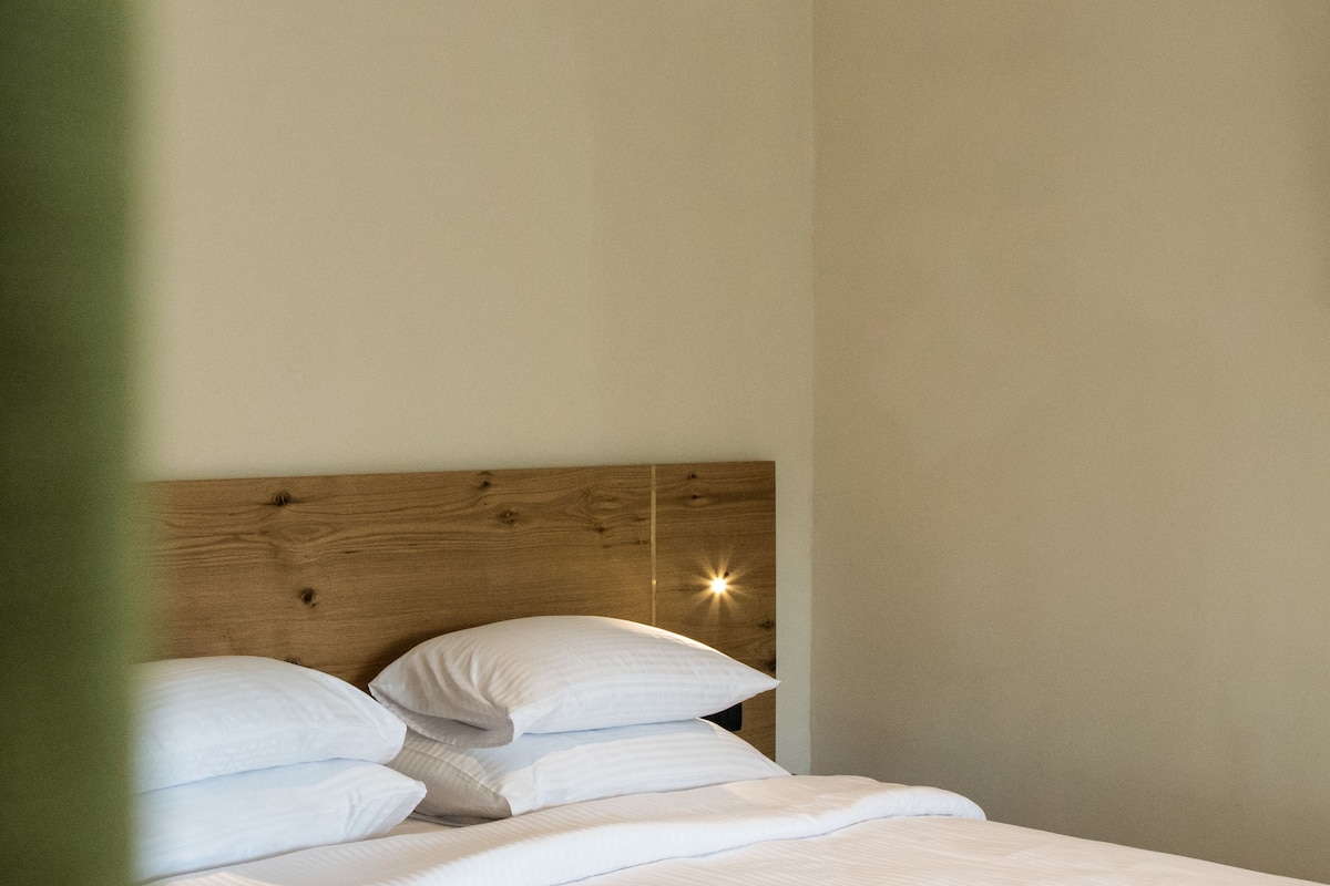 A neatly made bed with white linens and a wooden headboard.