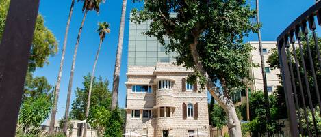 A stone building with a central courtyard, surrounded by palm trees and greenery.