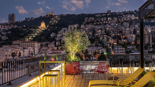 A rooftop terrace with yellow chairs, a table, and a potted plant. - The Schumacher Hotel Haifa (Haifa)