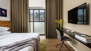 A hotel room with a bed, a desk with a chair, a TV, and a window with curtains. - The Schumacher Hotel Haifa (Haifa)