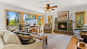 A living room with a fireplace, a television, and large windows. - RMR: Three Bear Tracks Home in Teton Village (Teton Village)