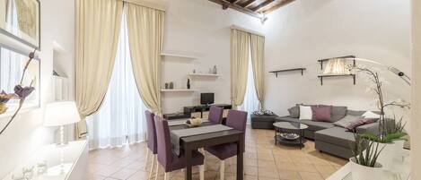 A living room with a dining table, sofa, and a TV.