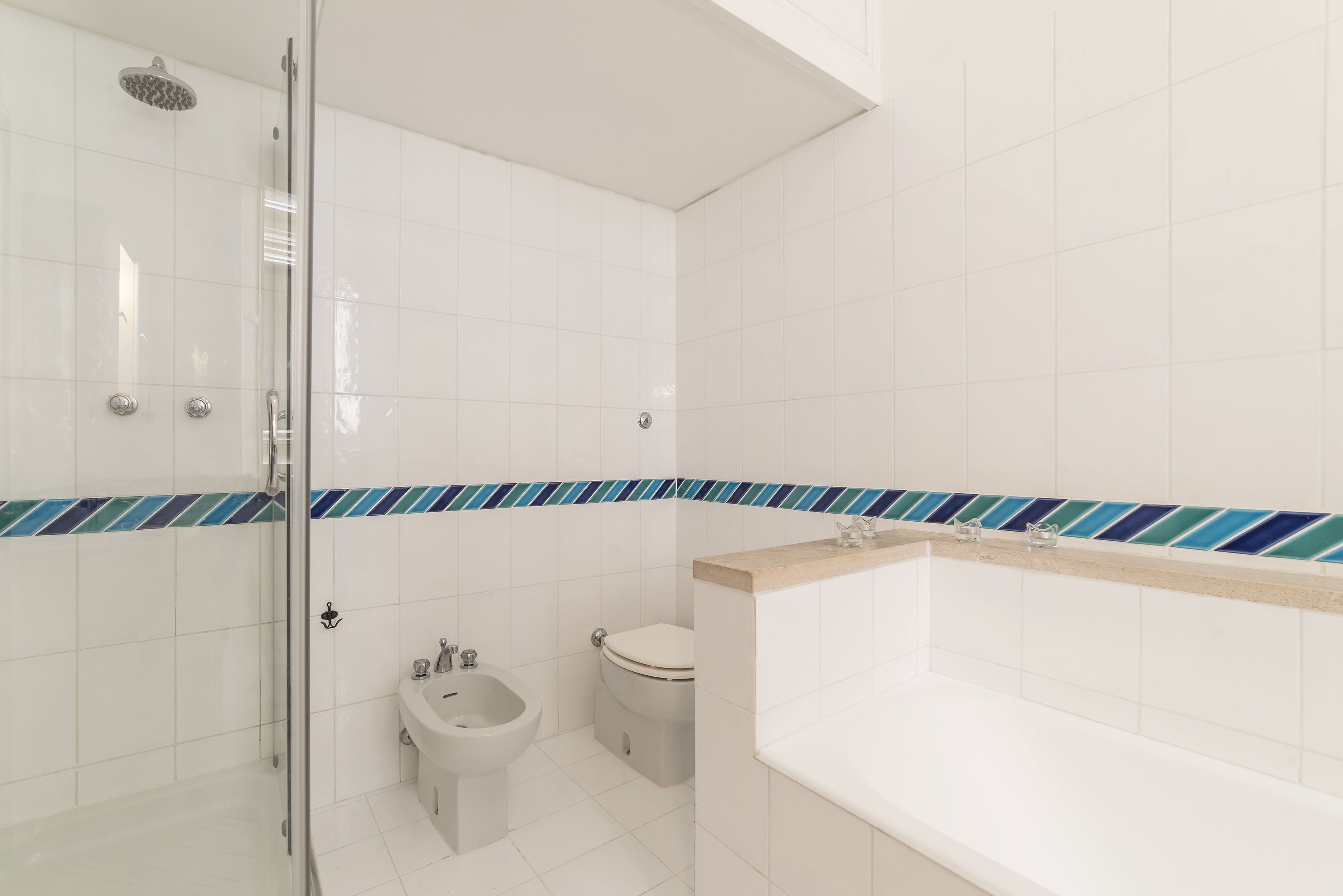 A modern bathroom with a glass shower enclosure, a bidet, a toilet, and a bathtub.