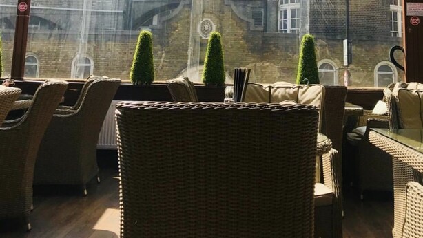 Une terrasse dotée de meubles en osier et offrant une vue sur un bâtiment historique, avec un dôme et une tour ronde.