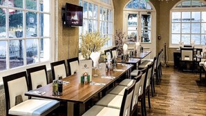 Une salle à manger spacieuse avec de hauts plafonds, de grandes fenêtres et un lustre.