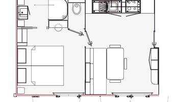 A floor plan of a hotel room with a bed, a desk, a chair, a small table, and a bathroom.