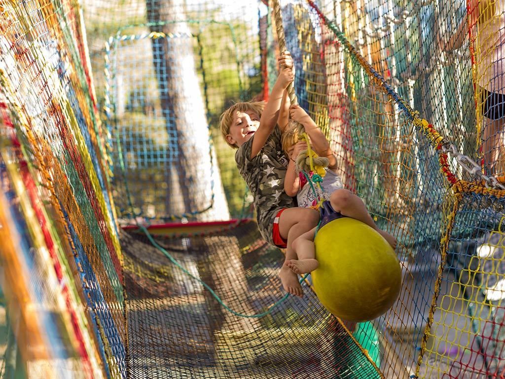 Un enfant qui grimpe sur une structure faite d’un réseau de cordes.