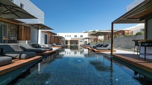 A modern pool area with lounge chairs and umbrellas, surrounded by contemporary architecture. - Elia Mykonos Resort (Mykonos)