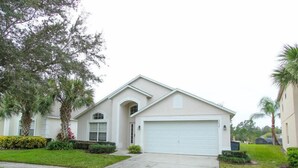 A single-story house with a garage, surrounded by well-maintained lawns and palm trees. - Ov2348 - Emerald Island Resort - 5 Bed 4.5 Baths Villa (Davenport)