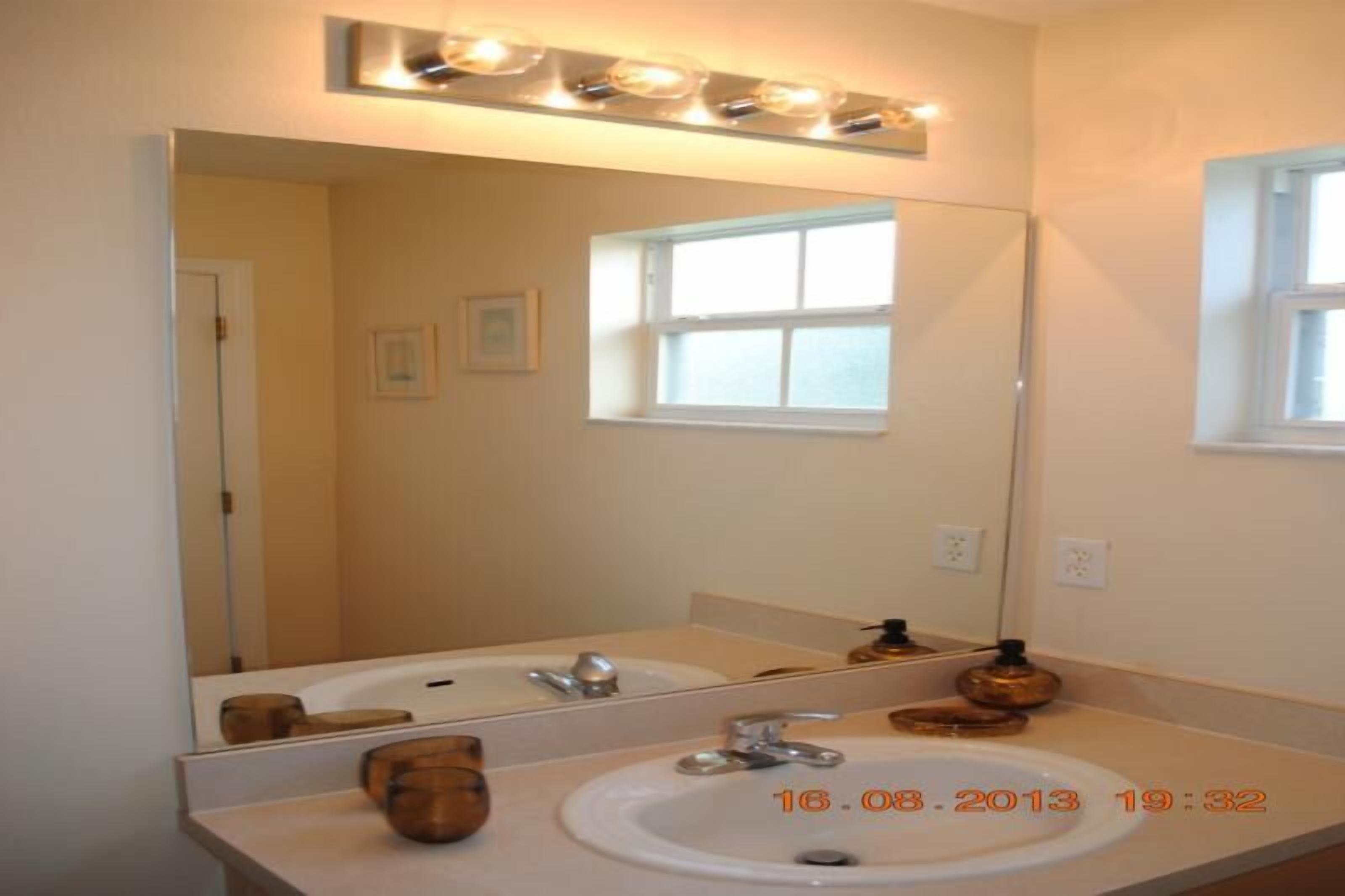 A bathroom with two sinks, a large mirror, and a window.