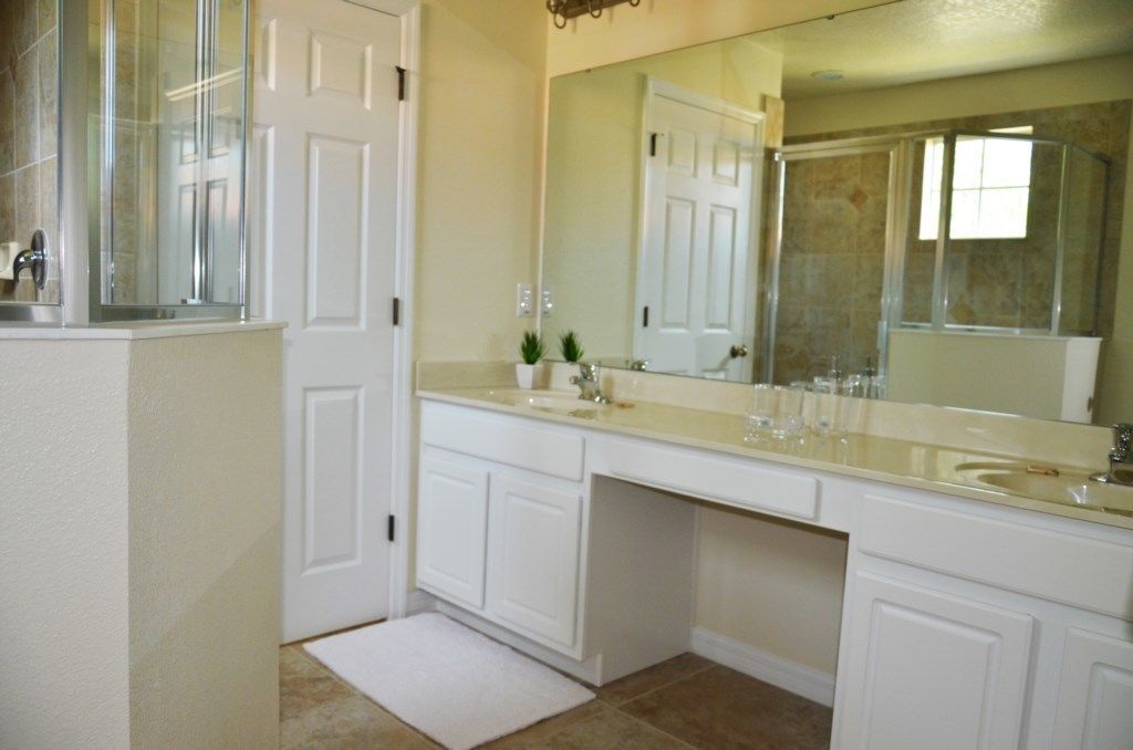 A bathroom with a double vanity, a large mirror, and a shower enclosure.